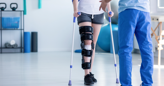 An image of a person in a knee brace on crutches talking with a healthcare professional emphasizing peptides for supporting muscle strength and tendon health post injury BPC-157 and GH-Release