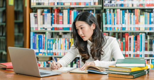 Image of woman studying in a library emphasizing the effects of Mind Tap Alpha GPC supplement for brain health, focus, and performance
